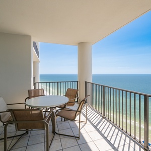 Relax on the spacious balcony, featuring a round table and chairs, with views of the shimmering coastline