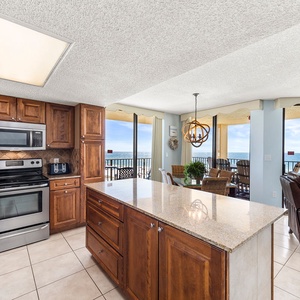Kitchen featuring rich wood cabinetry, stainless appliances, granite countertops, and a view of the beach