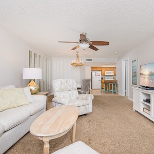 Relax in the inviting living area with comfortable seating, a large TV, and easy access to the kitchen and dining space
