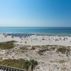 Enjoy stunning views from the balcony, featuring a spacious table and comfortable seating overlooking the sunny beach