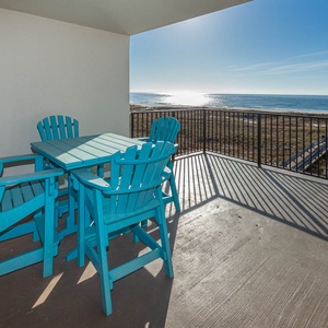 Bright turquoise patio table on the expansive balcony, offering a tranquil view of the beach and glistening gulf waters