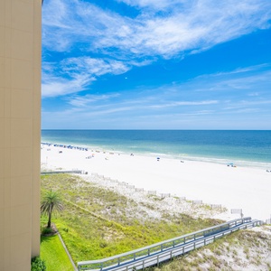 Enjoy a breathtaking beachfront view with white sand and vibrant umbrellas from this inviting balcony