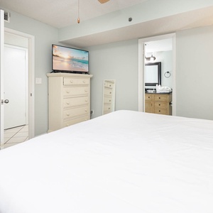 This cozy bedroom features a comfortable king bed, a TV for entertainment, and an adjoining bathroom with stylish cabinetry