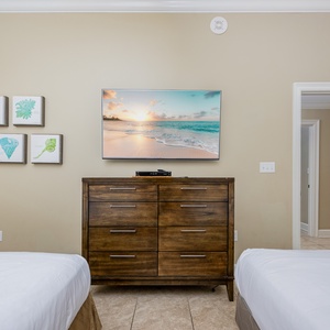Relax in this guest bedroom with two queen beds, a stylish dresser, and coastal artwork