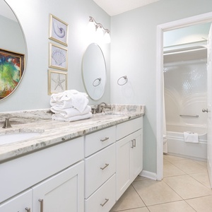 Experience a stylish master bathroom with a marbled countertop, modern fixtures, and vibrant art