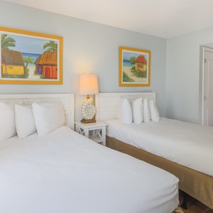 This inviting bedroom features two comfortable beds, vibrant artwork, and a warm atmosphere perfect for relaxation