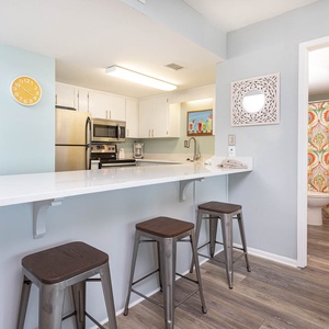This kitchen features stainless appliances, a bright countertop, and a cozy bar area with stylish stools for casual dining