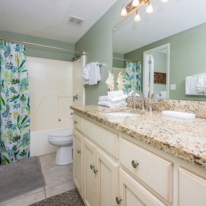 Experience the guest bathroom with a spacious vanity, colorful shower curtain, and fresh towels for your convenience