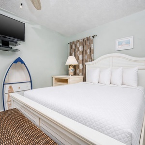 This guest bedroom features a plush bed, a mounted TV, and charming nautical decor, perfect for a relaxing stay