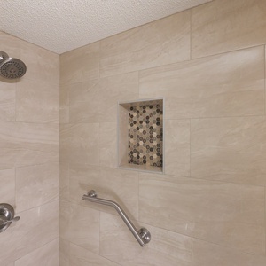 Stylish walk-in shower featuring elegant tile work and a convenient shower rail for added safety
