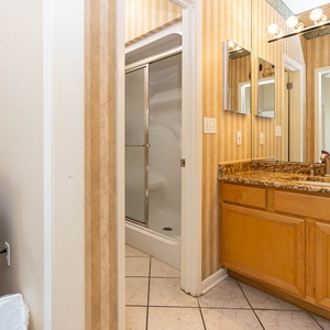 Master bath features a granite countertop, a walk-in shower, and elegant striped wallpaper for a refreshing ambiance