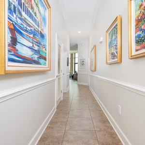 Brightly lit hallway adorned with colorful artwork, leading to a cozy living area with inviting natural light
