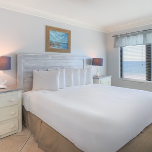 The master bedroom features a plush king bed and stunning beachfront views through large windows