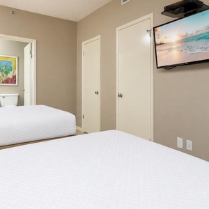 Relax in this guest room with two comfortable double beds, a mounted TV, and vibrant artwork