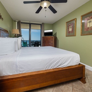 Cozy master bedroom featuring a king bed, vibrant green walls, and a balcony view with comfortable seating