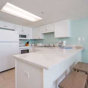 Prepare meals at the kitchen bar with two wooden stools, surrounded by cheerful aqua walls and bright lighting