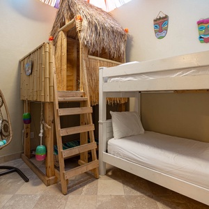 Colorful decor enhances this playful bunk room in the indoor master patio featuring two twin bunks and a hanging chair