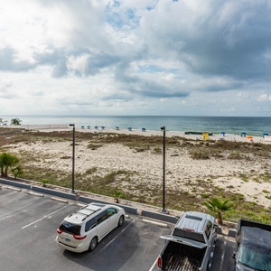 This balcony view showcases a serene beachfront with blue umbrellas, inviting guests to relax and enjoy the coastal scenery