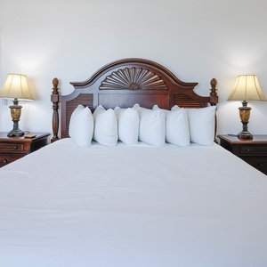 Relax in this inviting master bedroom featuring a king bed adorned with fluffy pillows and elegant bedside lamps
