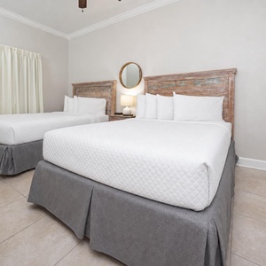 Unwind in this guest bedroom featuring two queen beds, soft linens, and warm decor for a restful stay