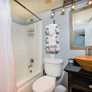 The guest bathroom features a stylish vessel sink, modern lighting, and plush towels for a refreshing experience