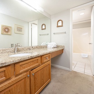 Enjoy the spacious master bathroom featuring a granite countertop, ample storage, and soft towels for your comfort