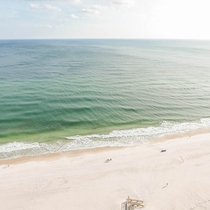 This inviting balcony space offers a stunning beachfront view with soft waves lapping against the white sand