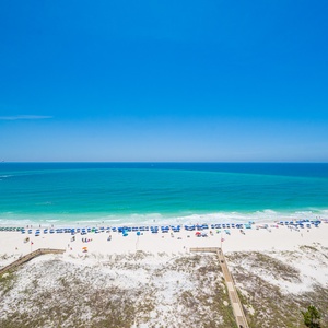 Gaze at the serene shoreline with colorful umbrellas and lounge chairs inviting you for a day of relaxation by the water
