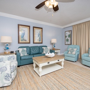 Relax in this inviting living area with comfortable seating, coastal decor, and views of the beach beyond the balcony