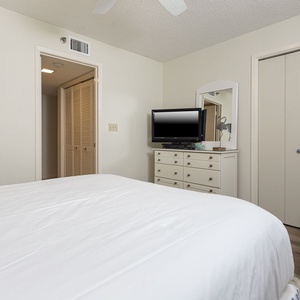 Unwind in this guest bedroom featuring a plush queen bed, a TV, and a comfortable seating area for relaxation