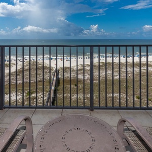 Relax on the balcony overlooking the beach, with views of white sand and inviting blue umbrellas lining the shore