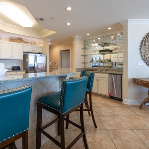 Inviting kitchen with granite countertops, stainless appliances, and stylish teal bar stools for casual dining