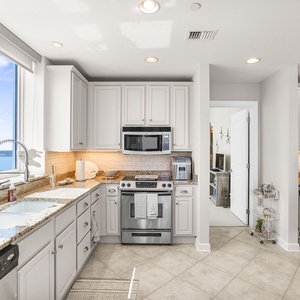 This kitchen features plentiful appliances, cabinetry, and meal prep space all with breathtaking panoramic views