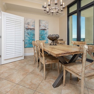 Dining area featuring a rustic wooden table, stylish chairs, and large windows showcasing a beautiful coastal view
