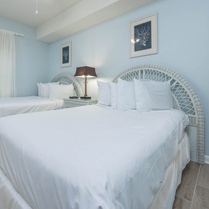 Relax in this inviting guest room with two double beds, soft linens, and soothing blue walls for a restful stay