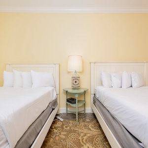 Inviting guest bedroom featuring two queen beds and a charming side table with a decorative lamp