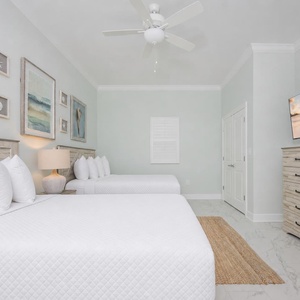 Rest in this tranquil guest bedroom featuring two double beds, coastal decor, and a TV