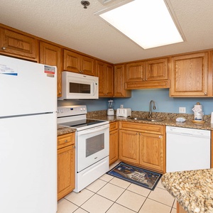 Bright kitchen features wooden cabinetry, granite countertops, and essential appliances, creating a welcoming cooking space