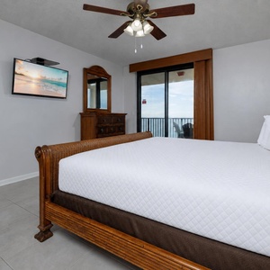 Rest in the serene master suite, featuring a cozy king bed, a TV for entertainment, and balcony doors to the beach view