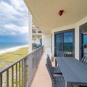 Spacious balcony features a dining table with seating and offers a serene view of the beach and Gulf beyond