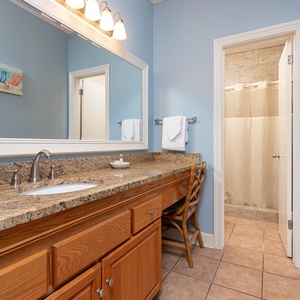 Master bath featuring a spacious vanity with a granite countertop, a large mirror, and a walk-in shower