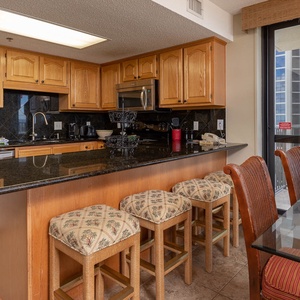 Warm wood cabinetry complements the granite countertops in this inviting kitchen area with a breakfast bar and seating