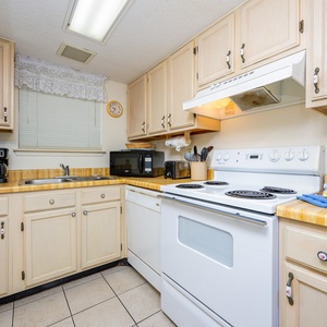 This kitchen features light cabinetry, essential appliances, and a cozy atmosphere perfect for meal preparation