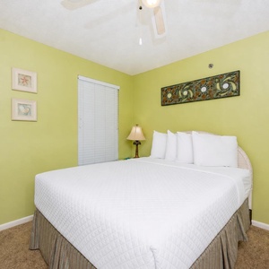 Guest bedroom with a cozy queen bed, charming decor, and a soothing green wall color for a relaxing stay