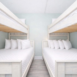 This cozy bedroom features two stylish bunk beds with plush white bedding, perfect for family stays