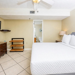 The cozy bedroom features a queen bed with plush pillows, a flat-screen TV, and a stylish wooden nightstand