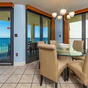 A glass dining table with beige chairs offers a perfect spot to enjoy meals while overlooking the tranquil beachfront