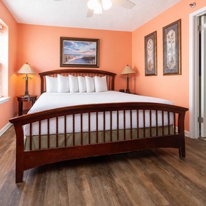 Coral walls complement a king bed adorned with plush white pillows, creating a welcoming vibe in this cozy retreat