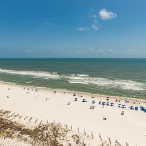 Gaze at the inviting shoreline with colorful umbrellas and gentle waves, perfect for a day of relaxation