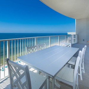 Enjoy meals at the spacious white table while taking in the breathtaking view of the beach from your balcony